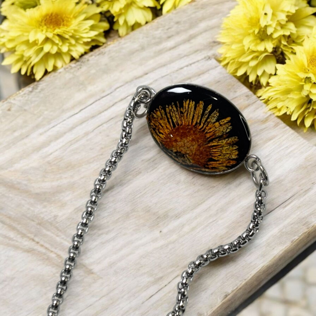 Artistic, handcrafted black pendant with vibrant yellow flower